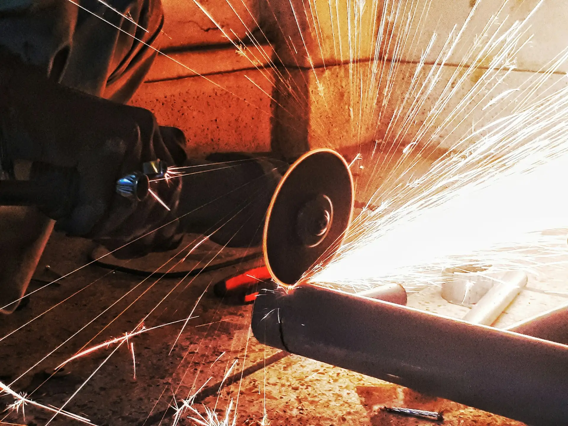 Angle grinder cutting a steel tube with a spray of sparks